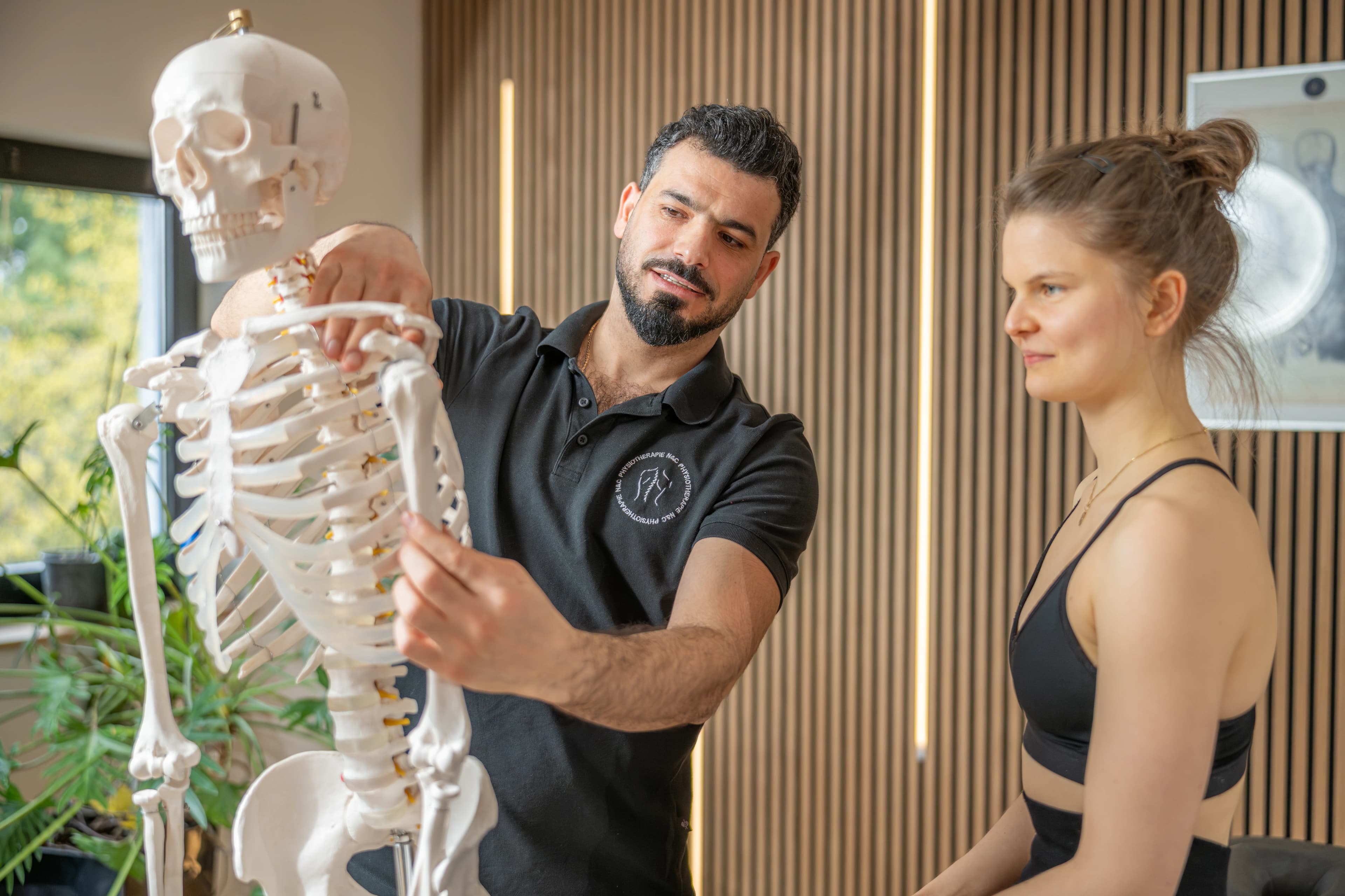 Ablauf einer Krankengymnastik-Behandlung: Therapeut erklärt mit Skelettmodell